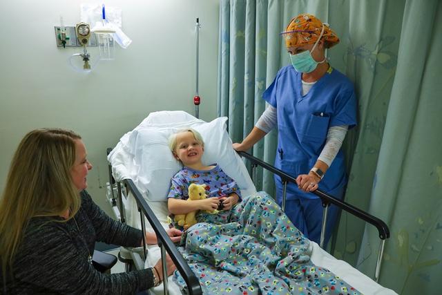 Child in Hospital Bed with Mom and a Surgeon 