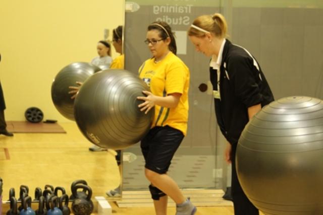 Two females using exercise balls in gym during a workout