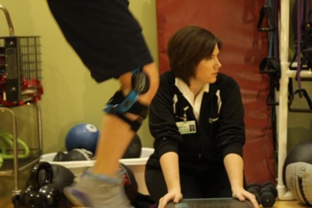 Female athletic trainer watching over people  in gym
